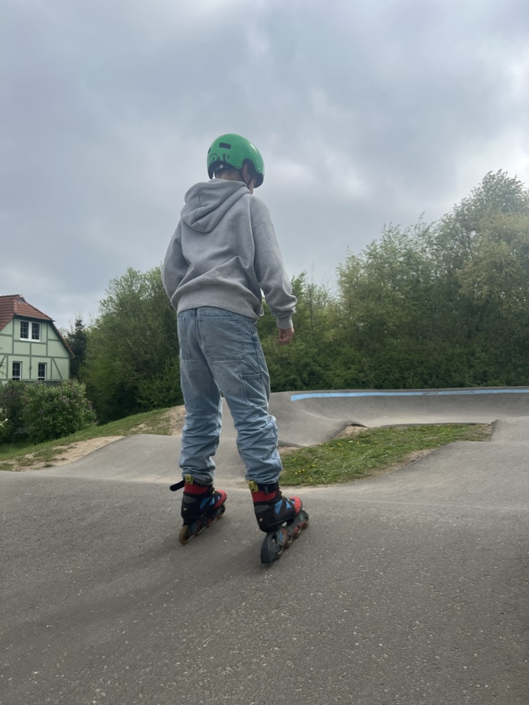 Kind fährt Rollerblades auf Pumptrack