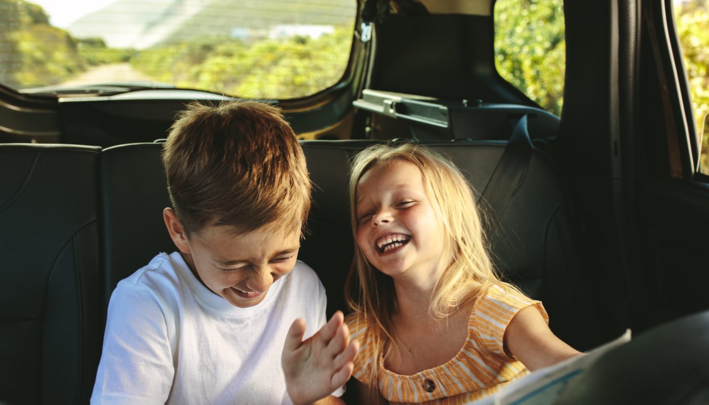 Kinder sitzen auf der Rückbank im Auto und spielen und haben Spaß
