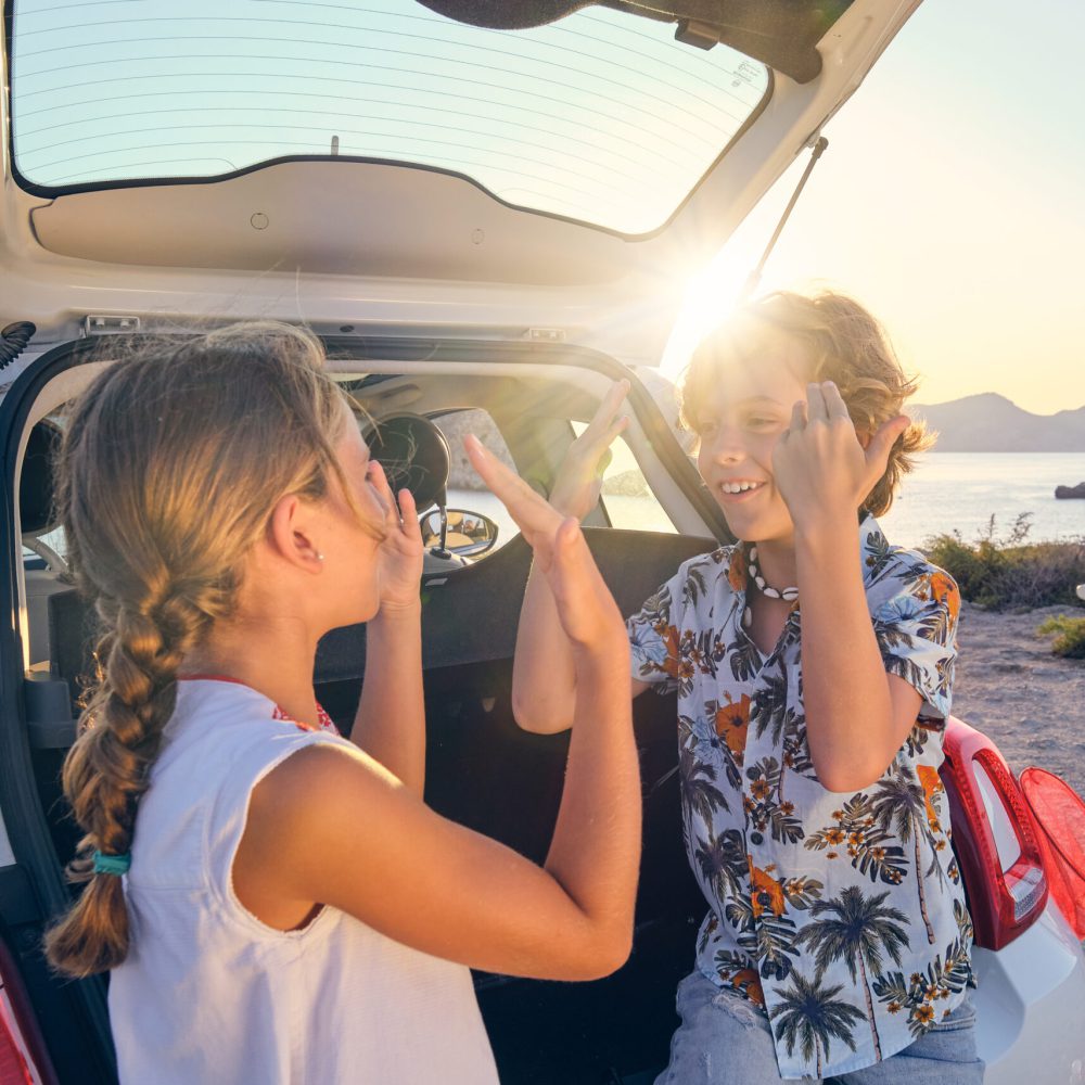 Kinder spielen fröhlich im Urlaub am Auto